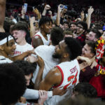 
              Maryland forward Donta Scott, center, and teammates are swarmed by students rushing the court after Maryland defeated Purdue 68-54 during an NCAA college basketball game, Thursday, Feb. 16, 2023, in College Park, Md. (AP Photo/Julio Cortez)
            