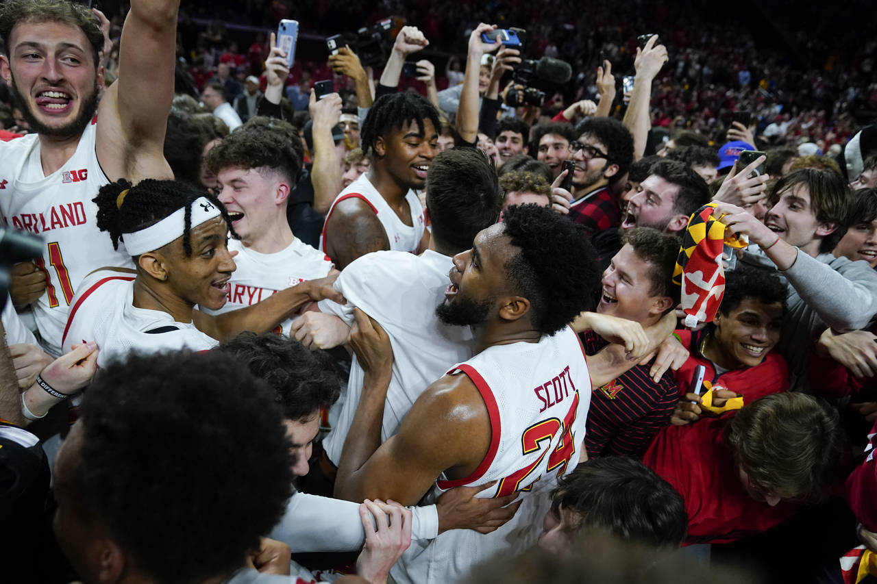Maryland forward Donta Scott, center, and teammates are swarmed by students rushing the court after...