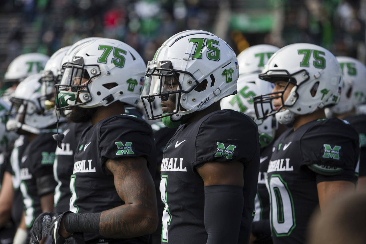 FILE - Marshall players wear a "75" decal on their helmets as they take the field for an NCAA colle...