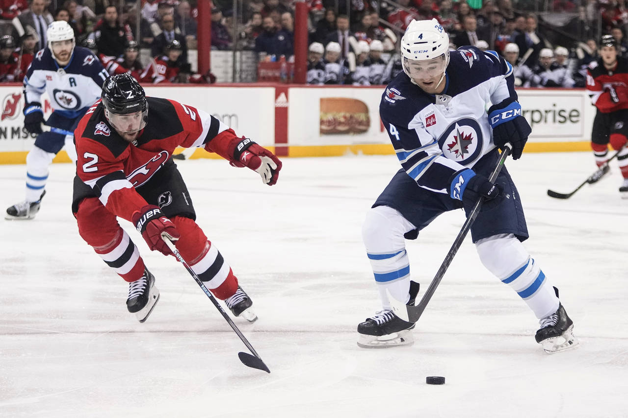 New Jersey Devils' Brendan Smith (2) defends against Winnipeg Jets' Neal Pionk (4) during the third...