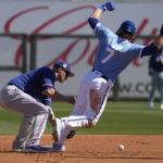 
              Kansas City Royals' Bobby Witt Jr. (7) beats the tag by Texas Rangers shortstop Corey Seager to steal first base during the first inning of a spring training baseball game Friday, Feb. 24, 2024, in Surprise, Ariz. (AP Photo/Charlie Riedel)
            