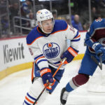 
              Edmonton Oilers left wing Zach Hyman, left, looks to pass the puck as Colorado Avalanche defenseman Bowen Byram, right, pursues in the second period of an NHL hockey game Sunday, Feb. 19, 2023, in Denver. (AP Photo/David Zalubowski)
            