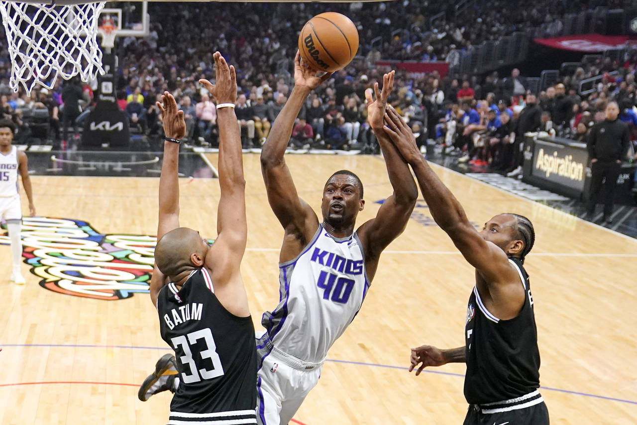 Sacramento Kings forward Harrison Barnes, center, shoots as Los Angeles Clippers forward Nicolas Ba...