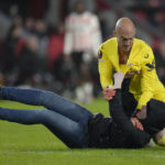 
              A PSV supporter, on the ground, attacks Sevilla's goalkeeper Marko Dmitrovic during the Europa League playoff second leg soccer match between PSV and Sevilla at the Philips stadium in Eindhoven, Netherlands, Thursday, Feb. 23, 2023. Sevilla won 3-2 on aggregate. (AP Photo/Peter Dejong)
            