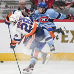 
              Montreal Canadiens' Josh Anderson is checked by New York Islanders' Alexander Romanov (28) during the third period of an NHL hockey game in Montreal, Saturday, Feb. 11, 2023. (Graham Hughes/The Canadian Press via AP)
            