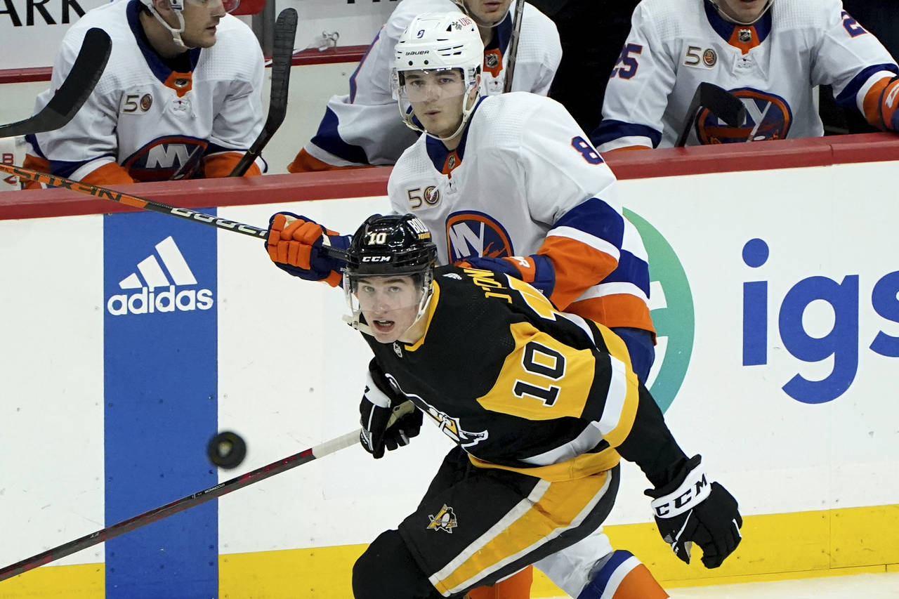 PIttsburgh Penguins left wing Drew O'Connor (10) reaches for the puck in front of New York Islander...