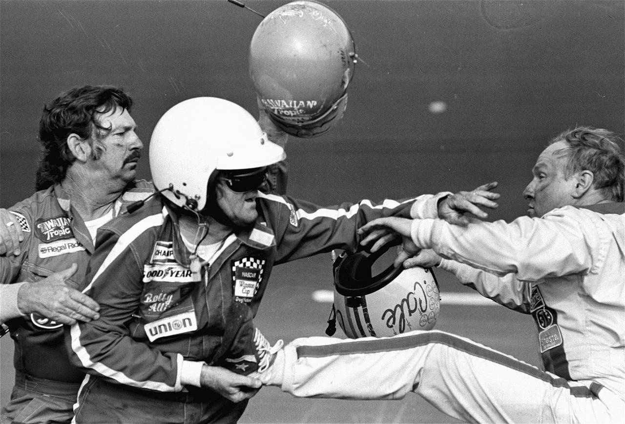 FILE - Bobby Allison, center, holds race driver Cale Yarborough's foot after Yarborough, right, kic...