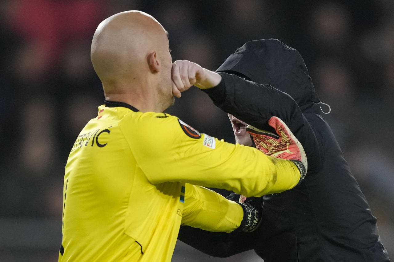 A PSV supporter punches Sevilla's goalkeeper Marko Dmitrovic in the face during the Europa League p...