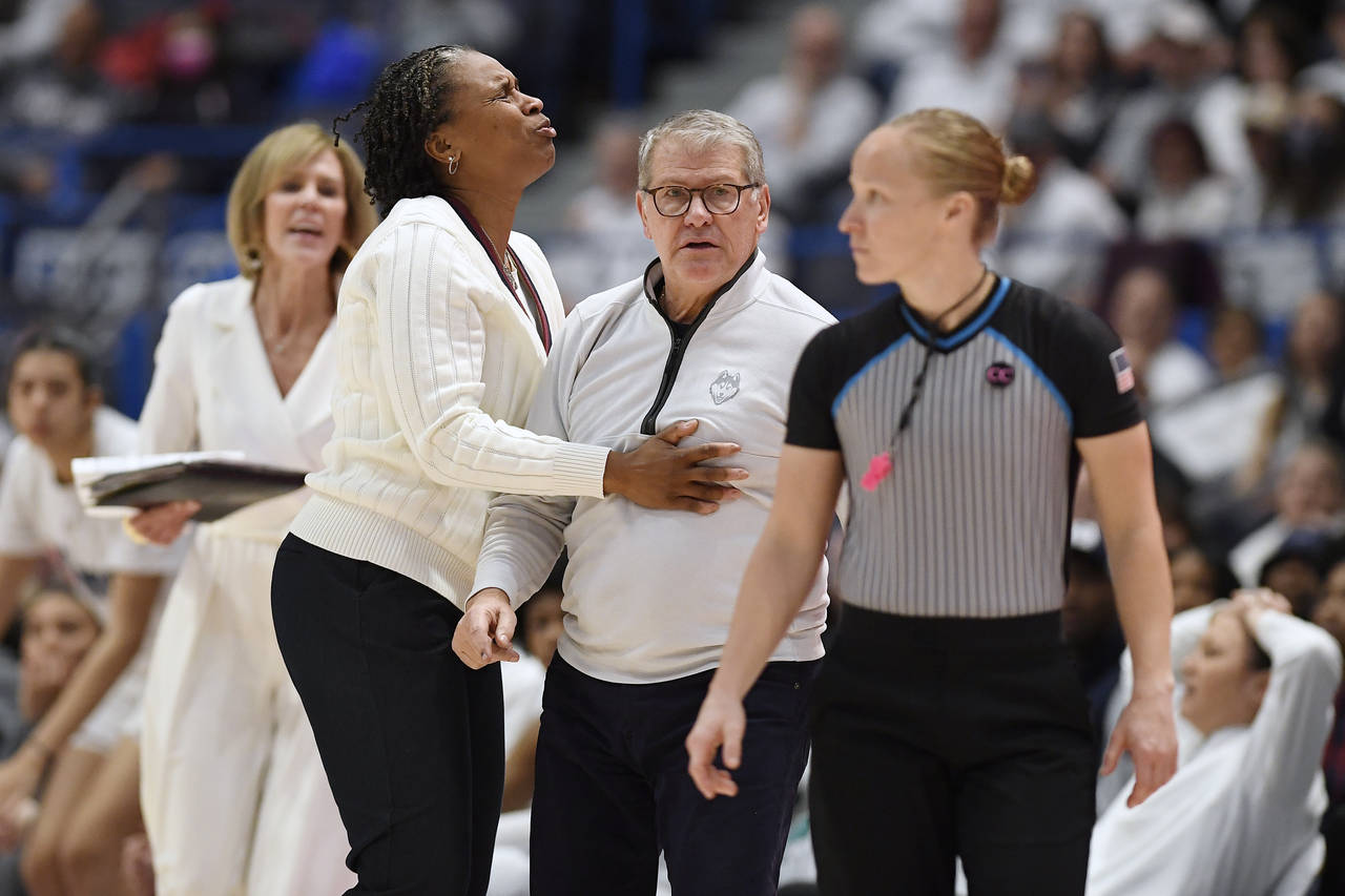 UConn head coach Geno Auriemma is held back by assistant coach Jamelle Elliott in the second half o...