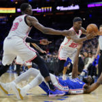 
              Philadelphia 76ers' Joel Embiid, bottom, and Miami Heat's Jimmy Butler, right, and Bam Adebayo chase a loose ball during the first half of an NBA basketball game, Monday, Feb. 27, 2023, in Philadelphia. (AP Photo/Matt Slocum)
            