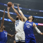 
              Minnesota Timberwolves center Rudy Gobert (27) shoots between Los Angeles Clippers forward Kawhi Leonard (2) and center Ivica Zubac (40) during the first half of an NBA basketball game Tuesday, Feb. 28, 2023, in Los Angeles. (AP Photo/Marcio Jose Sanchez)
            
