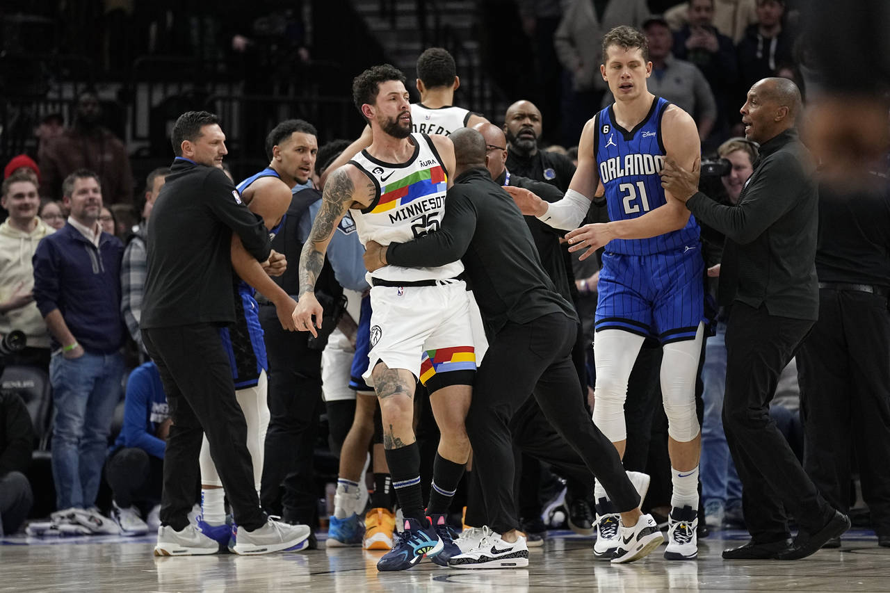 Minnesota Timberwolves guard Austin Rivers, middle, is held back after participating in a scrum wit...