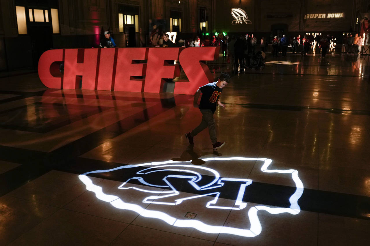A boy runs across a logo for the Kansas City Chiefs NFL football team while attending a display Thu...