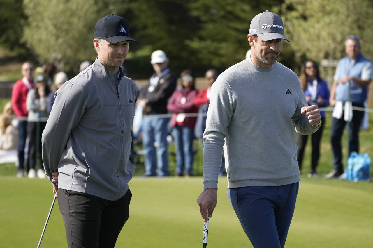 Buster Posey, left, and Aaron Rodgers watch during the putting challenge event of the AT&T Pebble B...