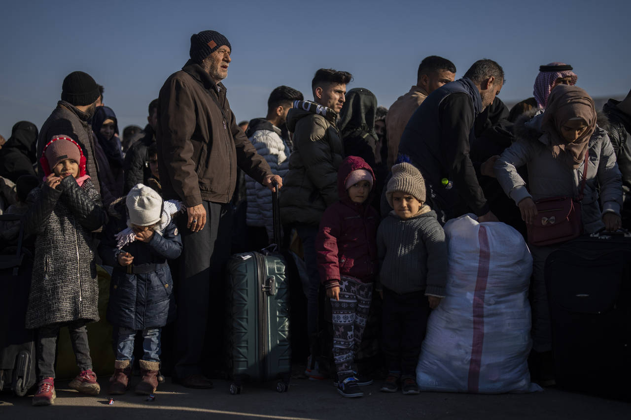 Syrians stand in a queue as they wait to return to their country from the Turkish crossing point of...