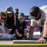 
              Fans sign their name on the finish line ahead of practice sessions before a NASCAR exhibition auto race at Los Angeles Memorial Coliseum, Saturday, Feb. 4, 2023, in Los Angeles. (AP Photo/Ashley Landis)
            