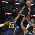 
              Minnesota Timberwolves guard Anthony Edwards, top right, shoots against Golden State Warriors forward Jonathan Kuminga (00) and forward Kevon Looney during the first half of an NBA basketball game in San Francisco, Sunday, Feb. 26, 2023. (AP Photo/Jeff Chiu)
            