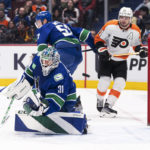 
              Vancouver Canucks goaltender Arturs Silovs redirects the puck into the corner, while Canucks' Tyler Myers and Philadelphia Flyers' Scott Laughton watch during the first period of an NHL hockey game Saturday, Feb. 18, 2023, in Vancouver, British Columbia. (Rich Lam/The Canadian Press via AP)
            