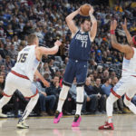 
              Dallas Mavericks guard Luka Doncic, center, looks to pass the ball as Denver Nuggets center Nikola Jokic, left, and forward Bruce Brown defend in the first half of an NBA basketball game Wednesday, Feb. 15, 2023, in Denver. (AP Photo/David Zalubowski)
            