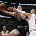 
              San Antonio Spurs' Jakob Poeltl (25) goes up to shoot while being fouled by Chicago Bulls' Nikola Vucevic (9) during the first half of an NBA basketball game Monday, Feb. 6, 2023, in Chicago. (AP Photo/Paul Beaty)
            