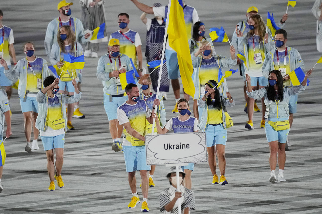 FILE - Olena Kostevych and Bogdan Nikishin, of Ukraine, carry their country's flag during the openi...