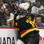 
              Vancouver Canucks' J.T. Miller hits Boston Bruins' Nick Foligno into the end boards during the second period of an NHL hockey game, Saturday, Feb. 25, 2023 in Vancouver, British Columbia. (Rich Lam/The Canadian Press via AP)
            