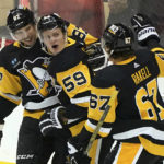 
              Pittsburgh Penguins left wing Jake Guentzel (59) celebrates after his goal against the New York Islanders with center Sidney Crosby (87) and right wing Rickard Rakell (67) during the first period of an NHL hockey game in Pittsburgh, Monday, Feb. 20, 2023. (AP Photo/Matt Freed)
            