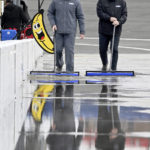 
              NASCAR Xfinity Series crew members Matt Schlytter and Matt Kempe use squeegees to remove water from the pits at Auto Club Speedway in Fontana, Calif., Saturday, Feb. 25, 2023. The Xfinity race was postponed. (Will Lester/The Orange County Register via AP)
            