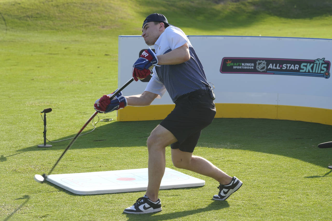 Nick Suzuki of the Montreal Canadiens, hits his first shot with a hockey stick during a golf skills...