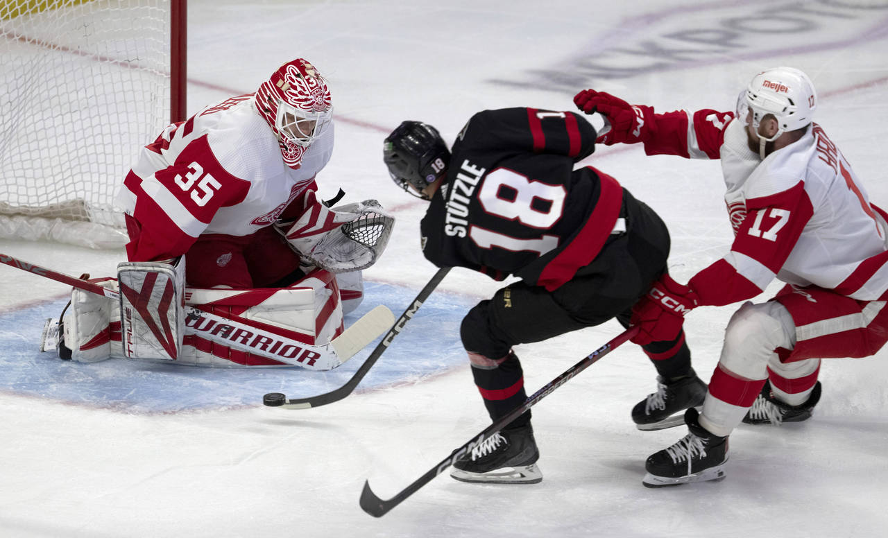 Detroit Red Wings defenseman Filip Hronek chases Ottawa Senators left wing Tim Stutzle as he shoots...