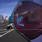 
              Eilish GrayWoulfe covers a fence with graphics outside State Farm Stadium, Friday, Feb. 3, 2023, in Glendale, Ariz. in preparation for the NFL Super Bowl LVII football game on Feb 12. (AP Photo/Matt York)
            