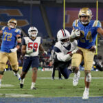 PASADENA, CALIFORNIA - NOVEMBER 12: Zach Charbonnet #24 of the UCLA Bruins scores a touchdown as Sterling Lane II #8 of the Arizona Wildcats attempts to tackle, to take a 28-24 lead, during the fourth quarter in a 31-28 Wildcats win at Rose Bowl on November 12, 2022 in Pasadena, California. (Photo by Harry How/Getty Images)