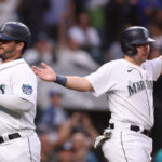 SEATTLE, WASHINGTON - JUNE 13: Mike Ford #20 and Cal Raleigh #29 of the Seattle Mariners score on a three-run RBI triple by Jose Caballero #76 during the sixth inning against the Miami Marlins at T-Mobile Park on June 13, 2023 in Seattle, Washington. (Photo by Steph Chambers/Getty Images)