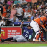 HOUSTON, TEXAS - JULY 07: Kolten Wong #16 of the Seattle Mariners scores in the fourth inning as Martin Maldonado #15 of the Houston Astros waits forf the ball at Minute Maid Park on July 07, 2023 in Houston, Texas. (Photo by Bob Levey/Getty Images)