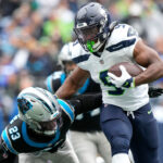 SEATTLE, WASHINGTON - SEPTEMBER 24: Kenneth Walker III #9 of the Seattle Seahawks stiff arms CJ Henderson #23 of the Carolina Panthers during the first quarter at Lumen Field on September 24, 2023 in Seattle, Washington. (Photo by Christopher Mast/Getty Images)