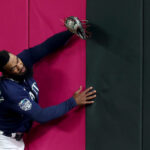 SEATTLE, WASHINGTON - SEPTEMBER 26: Teoscar Hernandez #35 of the Seattle Mariners crashes into the outfield wall after making a leaping catch for an out against the Houston Astros during the sixth inning at T-Mobile Park on September 26, 2023 in Seattle, Washington. (Photo by Steph Chambers/Getty Images)