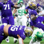 LAS VEGAS, NEVADA - DECEMBER 01: Dillon Johnson #7 of the Washington Huskies runs over Evan Williams #33 of the Oregon Ducks while scoring a rushing touchdown during the first quarter during the Pac-12 Championship at Allegiant Stadium on December 01, 2023 in Las Vegas, Nevada. (Photo by Ian Maule/Getty Images)