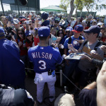 Seattle Seahawks quarterback Russell Wilson signs autographs for a large crowd in attendance to watch him work out with the Texas Rangers during spring training baseball practice, Monday, March 3, 2014, in Surprise, Ariz. (AP Photo/Tony Gutierrez)