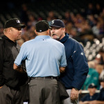 After Mariners pitcher Felix Hernandez hit two Marlins batters during the second inning, Mariners skipper Eric Wedge (right) meets with the umpires.
