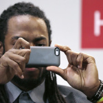 Seattle Seahawks cornerback Richard Sherman takes a photograph of the audience during a panel discussion at Harvard University in Cambridge, Mass., Wednesday, April 23, 2014. Sherman told Harvard students that he refuses to back down from his rant after the NFC championship game because he wants to "educate the uneducated." (AP Photo/Charles Krupa)
