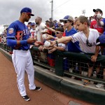 
              Texas Rangers' Ian Desmond signs autographs before a spring training baseball game against the Seattle Mariners Sunday, March 6, 2016, in Surprise, Ariz. (AP Photo/Charlie Riedel)
            