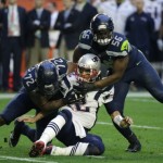 New England Patriots quarterback Tom Brady (12) is hit by Seattle Seahawks defensive end Michael Bennett (72) and Cliff Avril after throwing an interception during the first half of NFL Super Bowl XLIX football game Sunday, Feb. 1, 2015, in Glendale, Ariz. (AP Photo/David Goldman)