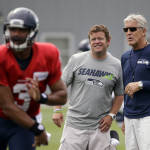 Seattle Seahawks head coach Pete Carroll, right, and general manager John Schneider watch as quarterback Russell Wilson throws at an NFL football training camp Monday, Aug. 3, 2015, in Renton, Wash. (AP Photo/Elaine Thompson)