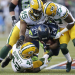 Seattle Seahawks running back Marshawn Lynch (24) is tackled by Green Bay Packers' Datone Jones (95), Sam Shields (37), and Morgan Burnett (42) as he rushes in the first half of an NFL football game, Thursday, Sept. 4, 2014, in Seattle. (AP Photo/Scott Eklund)