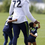 Seattle Seahawks defensive end Michael Bennett walks with his daughters Peyton, 7, left, and Blake, 3, right, Saturday, Aug. 2, 2014, after a session of NFL football training camp in Renton, Wash. (AP Photo/Ted S. Warren)