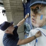 Craig Brookbush, of Rainier Industries, smoothes out a new window display on the exterior of Safeco Field in Seattle featuring Seattle Mariners pitcher Felix Hernandez, Thursday, Jan. 28, 2016. Brookbush said that most of the player signs around the stadium will be replaced ahead of the upcoming baseball season. (AP Photo/Ted S. Warren)