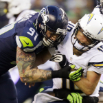 Seattle Seahawks defensive end Cassius Marsh (91) puts a hit on San Diego Chargers quarterback Kellen Clemens after Clemens got the ball off in the first half of a preseason NFL football game, Friday, Aug. 15, 2014, in Seattle. (AP Photo/Stephen Brashear)