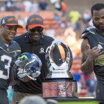 Michael Irvin, Pro Bowl legend team captain and Pro Football Hall of Famer, center, takes a photo with Seattle Seahawks quarterback Russell Wilson (3), who was named the offensive player of the game, and defensive end Michael Bennett, of Team Irvin, right, after the NFL Pro Bowl football game, Sunday, Jan. 31, 2016, in Honolulu. Team Irvin won 49-27. (AP Photo/Eugene Tanner)