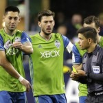 Seattle Sounders forward Clint Dempsey, left, rips his CONCACAF Champions League patch off of his jersey after teammate Andreas Ivanschitz, right rear, was given a yellow card for dissent by referee Oscar Reyna, front right, as Sounders captain Brad Evans, second from left, watches during the second half of a CONCACAF Champions League soccer quarterfinal against Club America, Tuesday, Feb. 23, 2016, in Seattle. The game ended in a 2-2 draw(AP Photo/Ted S. Warren)