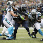 Seattle Seahawks running back Marshawn Lynch, center, runs between Carolina Panthers' Luke Kuechly, left, and Mario Addison (97) in the first half of an NFL football game, Sunday, Oct. 18, 2015, in Seattle. (AP Photo/Elaine Thompson)